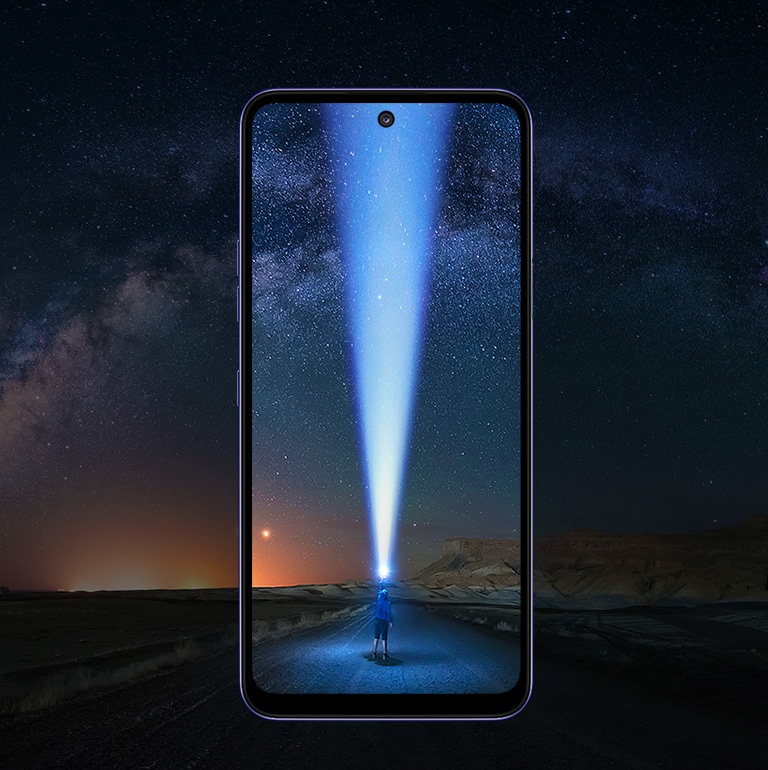 Rapaz apontando uma lanterna para o céu na estrada.